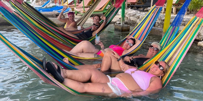 GO Babes women relaxing in colorful hammocks during a small-group travel retreat, sharing laughter and connection.